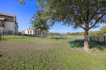 A park with a tree and a bench in front of a fence